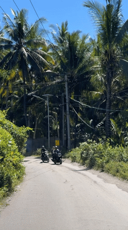 Three motorcyclists travel road in Apitaik, Indonesia