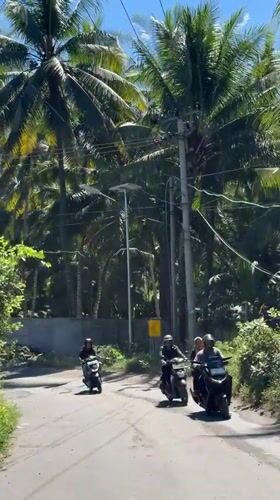 Three motorcyclists travel road in Apitaik, Indonesia