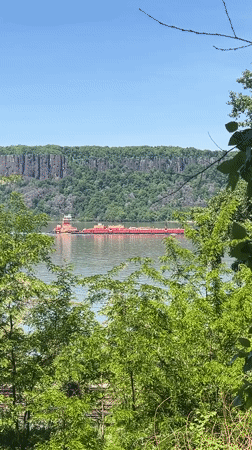 Tugboat tows barge across river near Yonkers cliffs