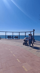 Couple strolls seaside promenade with swings in Shcholkine, Ukraine