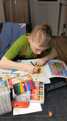 Boy focuses on coloring book at Moscow table