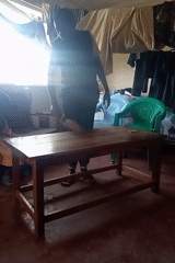 Man cleans and organizes cluttered room in Lumakanda, Kenya