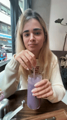 Woman enjoys purple smoothie at Milan cafe
