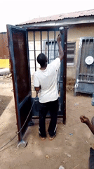 Man spray paints metal security door outdoors Thursday morning