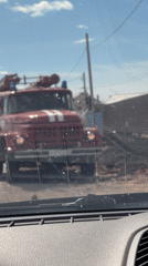 Red fire truck with blue lights observed through windshield