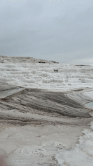 Tourists explore Pamukkale's white travertine terraces on overcast morning