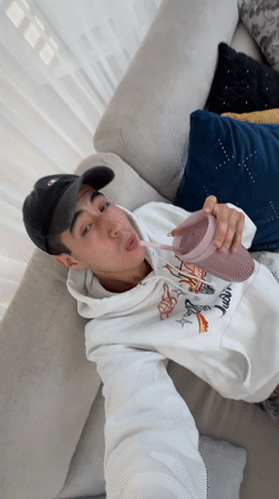 Young man enjoys purple smoothie on couch in Mexico