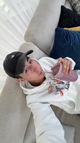 Young man enjoys purple smoothie on couch in Mexico
