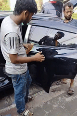 Black car cleaned and serviced on a Dhaka street