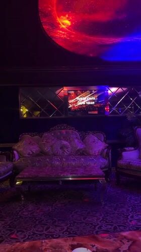 Woman poses in purple-lit karaoke room in Tbilisi