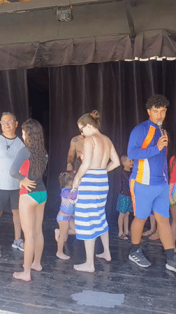 Poolside gathering features presenter and dancing families in Porlamar
