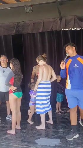 Poolside gathering features presenter and dancing families in Porlamar