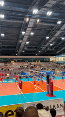 Indoor volleyball match between red and blue teams observed