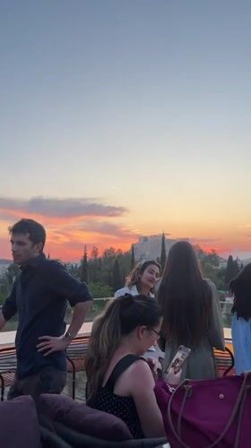 Athens rooftop gathering enjoys sunset view near Acropolis