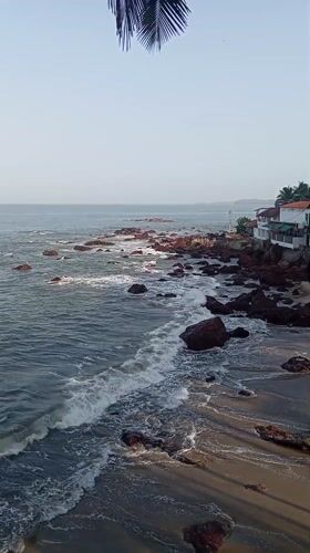 Ocean waves crash against rocks at Querim beach