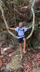 Hiker rests on tree branch near waterfall in Thailand