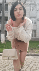 Young woman in white sweater observed standing outdoors