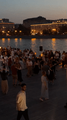 Group dancing gathering filmed near waterfront at dusk
