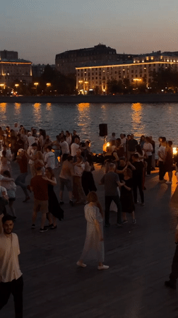 Group dancing gathering filmed near waterfront at dusk