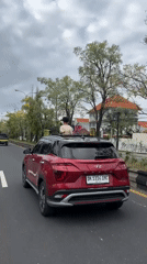 Person stands through sunroof of moving car in Denpasar