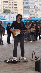 Electric guitar street performance in a paved outdoor space