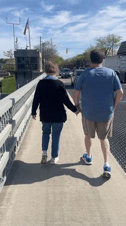 Couple watches yacht pass through raised drawbridge in Charlevoix