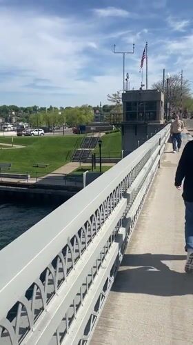 Couple watches yacht pass through raised drawbridge in Charlevoix