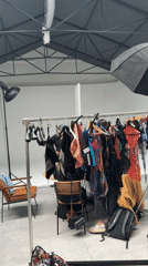 Milan studio glimpse shows clothing rack, person partially visible