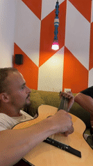 Young man plays guitar on green sofa in São Paulo