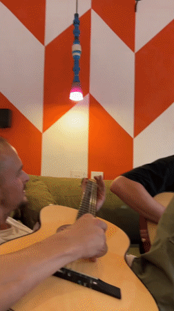 Young man plays guitar on green sofa in São Paulo