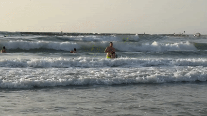 Crowded summer beach day in Netanya, parasailing overhead