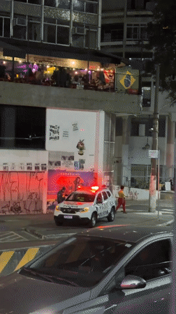 Police car lights flash during nighttime street stop in São Paulo