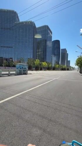 Morning cyclist rides past modern buildings in Beijing district