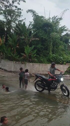 Children play in river as motorcycle passes, Saweuk Indonesia
