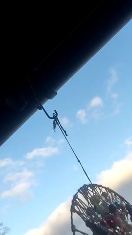 The video shows a dreamcatcher hanging from a rope against a backdrop of a partly cloudy sky. The view then shifts to showcase a cityscape dotted with buildings, rooftops, and construction cranes. The sky exhibits a contrast between clear blue patches and a broad band of gray clouds.