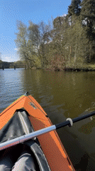 Kayaker enjoys sunny day on lake in orange kayak