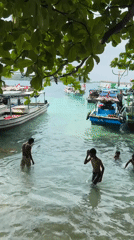 Boys play in shallow water near Indonesian boats in Jakarta