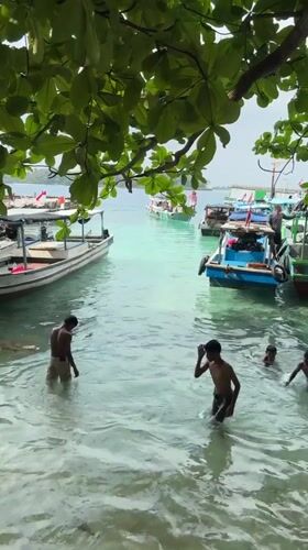 Boys play in shallow water near Indonesian boats in Jakarta