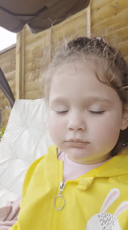 Child in yellow raincoat plays in London backyard