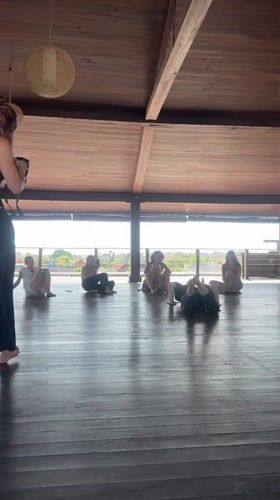 Dance instructor demonstrates moves to seated group in Mengwi