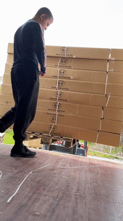 Workers load shipping containers with boxes in Bulgarian industrial facility