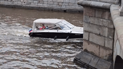 Motorboat travels waterway near Lomonosov Bridge, St. Petersburg