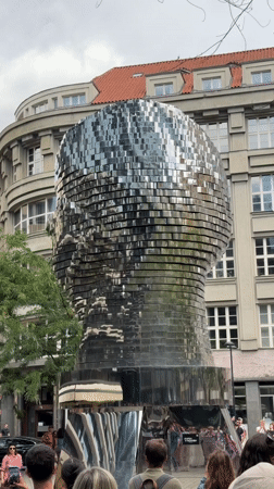 Prague's iconic reflective metallic head sculpture in a city square