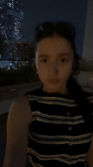 Woman films nighttime selfies with illuminated Burj Khalifa in Dubai