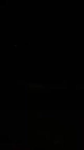 The video is entirely dark, with no visible objects or people. There is a slight horizontal demarcation suggesting a horizon line. A single, very faint light is visible in the upper left corner. No actions or interactions can be discerned due to the complete lack of illumination.