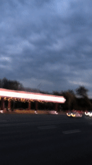 Neon-lit gas station glows along a busy Moscow road at dusk