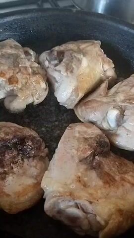 The media file shows a close-up, overhead view of chicken pieces cooking in a dark, non-stick frying pan. The chicken pieces appear to be thighs, with some skin still attached. They are browned on one side and have a light, golden color on the other. Some pieces show visible seasoning, like pepper. The pan is on a stovetop, with a hint of a metal pot or lid visible in the upper right corner. The lighting suggests it's daytime, likely indoors. The scene is focused on the cooking process itself, emphasizing the texture and color of the chicken as it sears. There is no visible text. The location context of Horenka, Ukraine is provided, but no specific visual cues in the image directly confirm this location. The overall impression is one of home cooking.