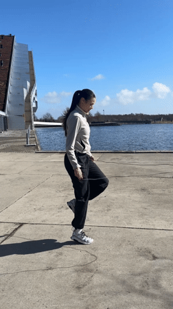Woman jump ropes by Copenhagen canal as swan swims nearby