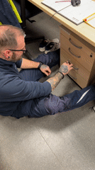 Man searches desk drawer while sitting on floor