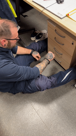 Man searches desk drawer while sitting on floor